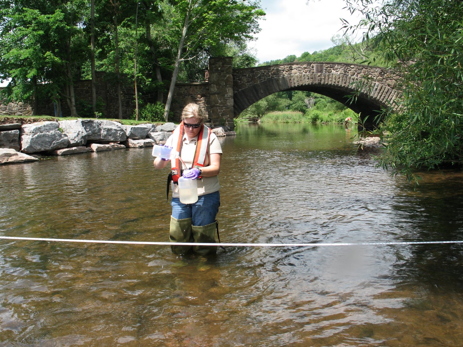 Hydrologist collecting a water quality sample in a stream